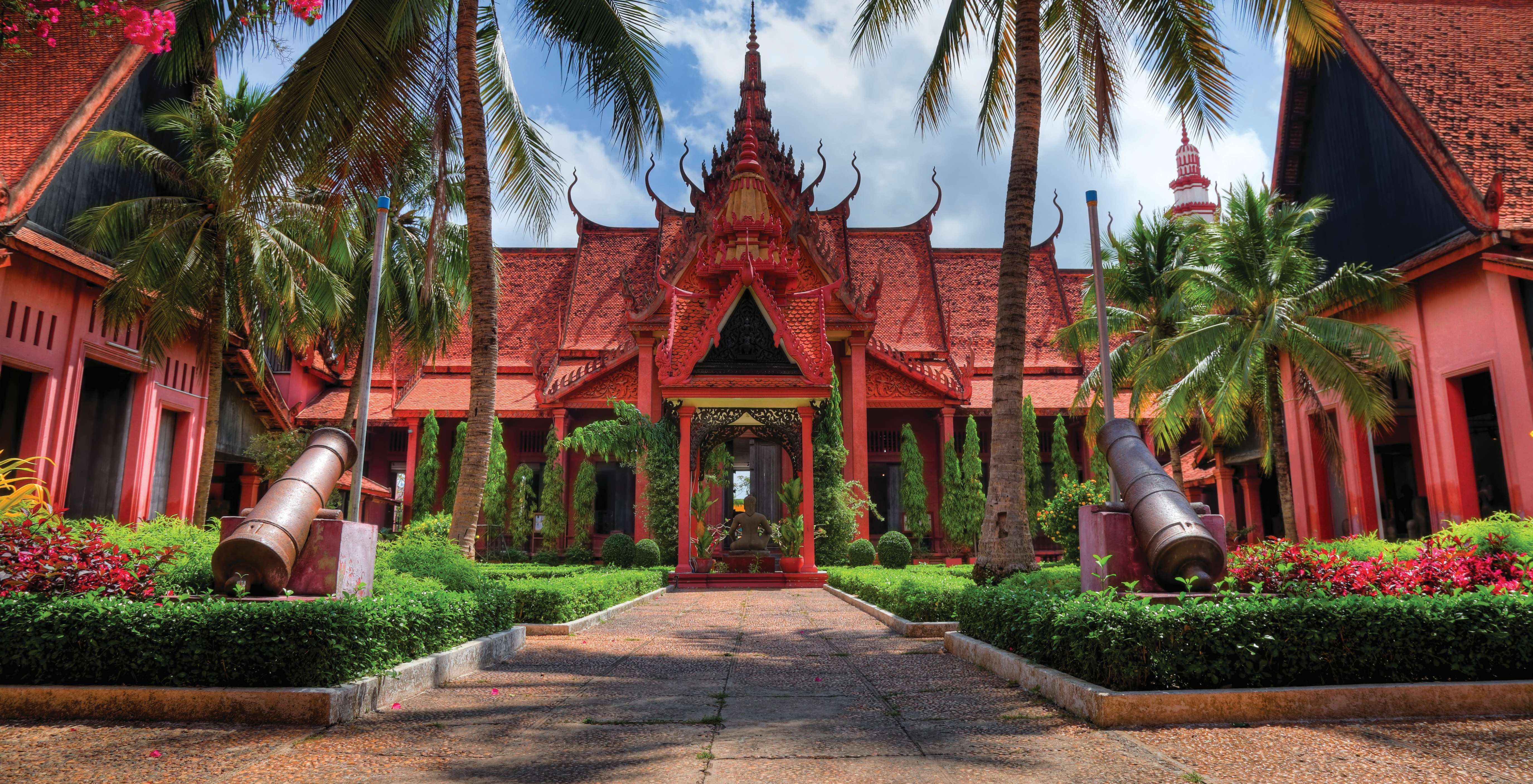 The ornate Khmer architecture of the Royal Palace Throne Hall against a bright blue sky.